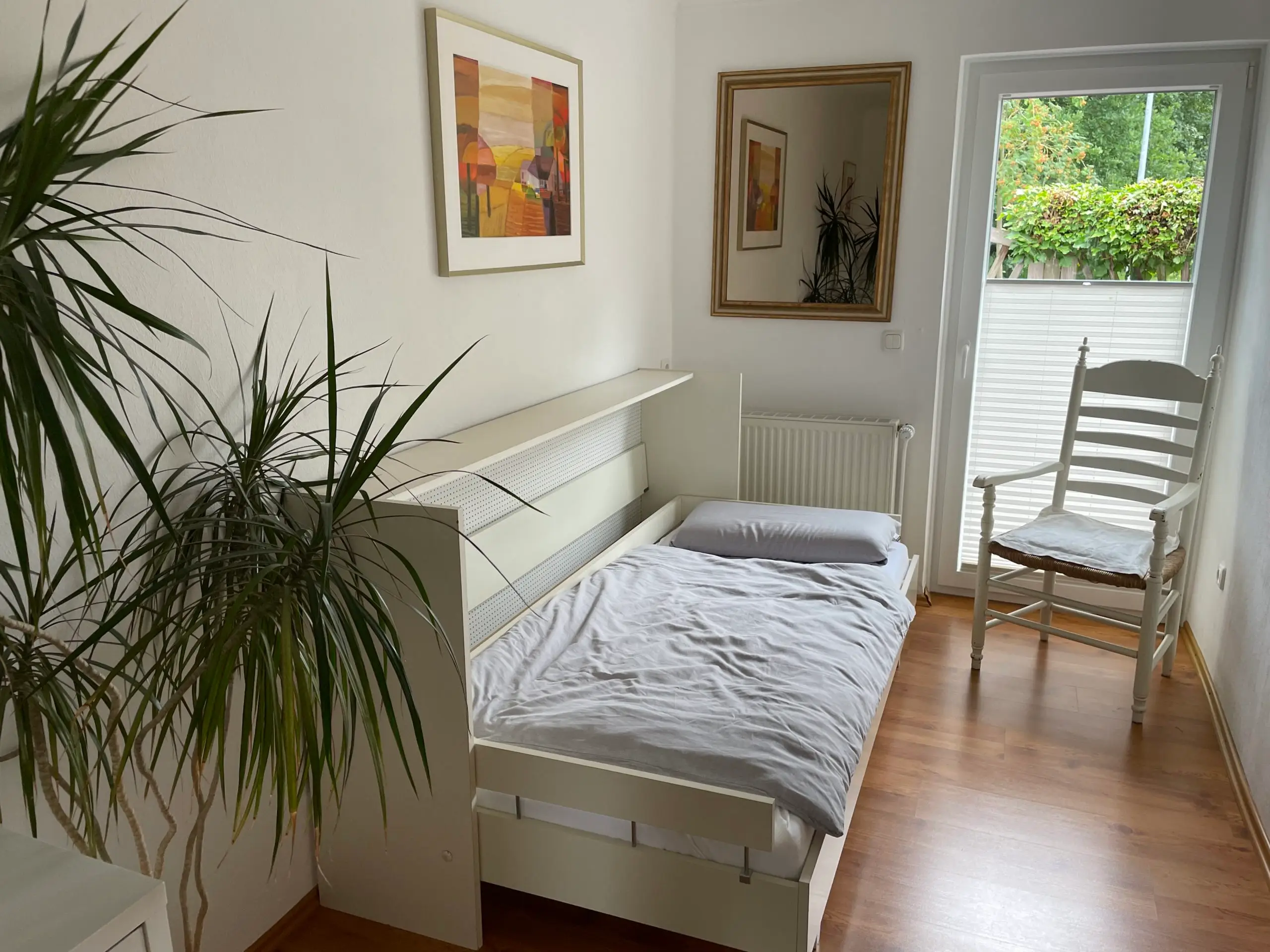Zweites Schlafzimmer mit ausgeklapptem Schrankbett und Tür zum Garten