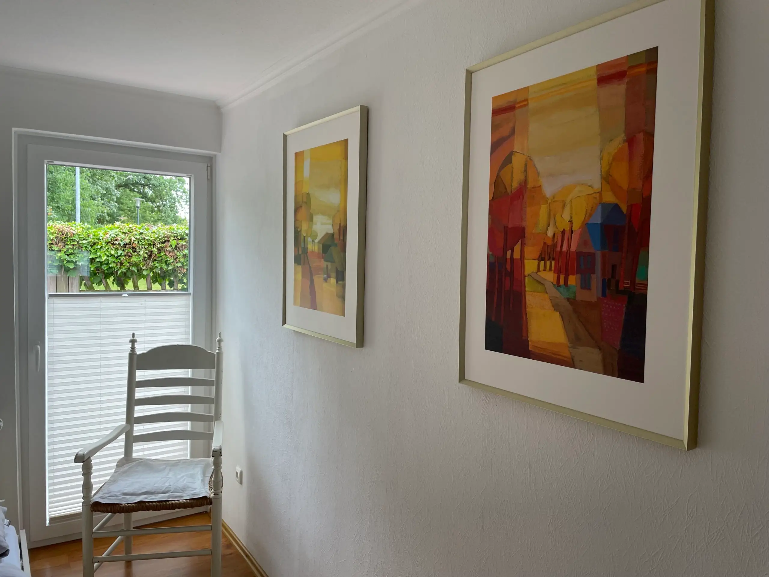 Zweites Schlafzimmer mit Bildern und Stuhl an der Gartentür